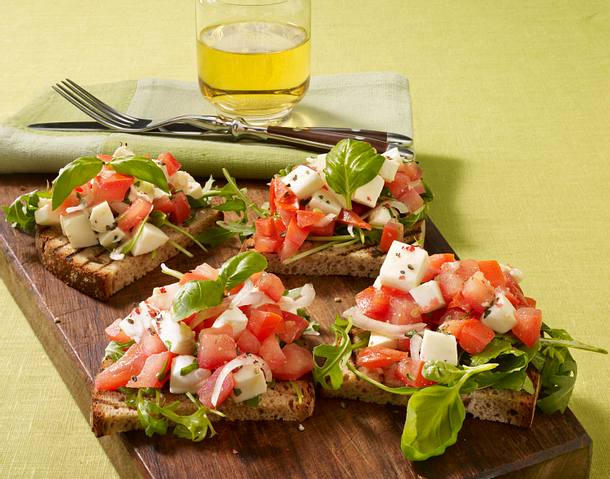 Bruschetta mit Tomaten-Mozzarella-Salat und Rauke Rezept | LECKER