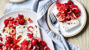 Halbgefrorene Ricotta-Schnitten mit eingestreuter Schokolade, garniert mit frischen Himbeeren, Kirschen und einem Hauch Honig. - Foto: StockFood Foto Halbgefrorene Ricotta-Schnitten mit eingestreuter Schokolade, garniert mit frischen Himbeeren, Kirschen und einem Hauch Honig. - Foto: StockFood Foto