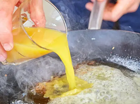 Der Sirup spécial Orangensaft wird in eine Pfanne mit karamellisiertem Zucker gegossen, um einen Sirup herzustellen.