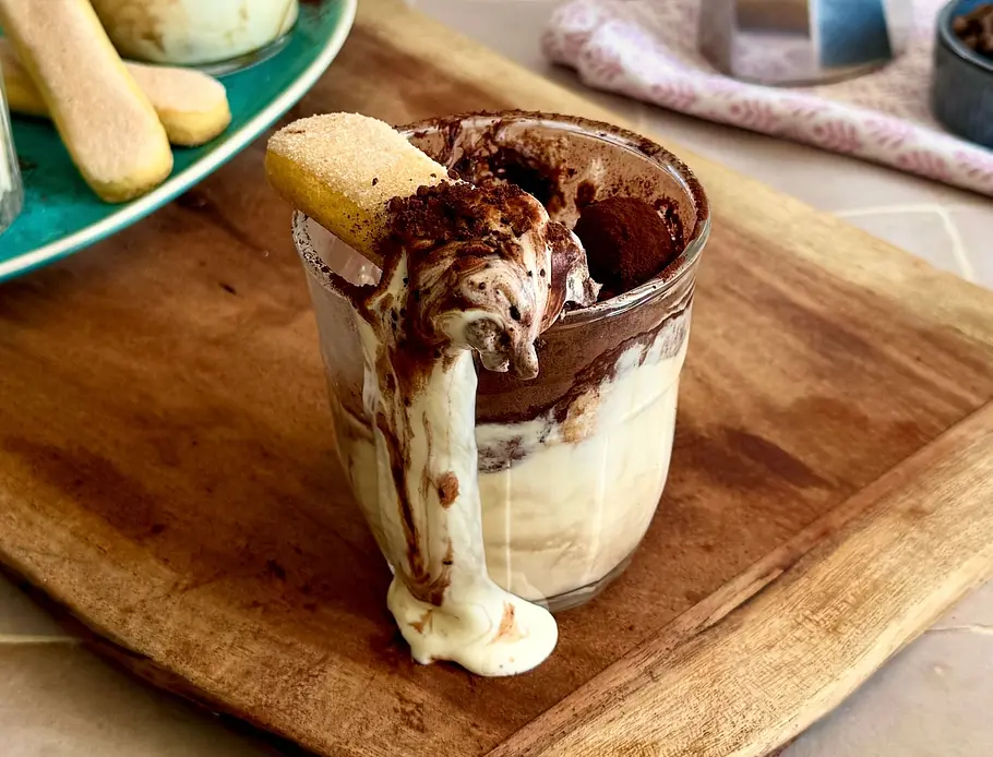 5 Minuten Tiramisu Rezept Ein Glas Tiramisu mit üppiger Mascarponecreme, dickem Kakaopulver und Löffelbiskuit. Etwas Creme läuft am Glas nach unten