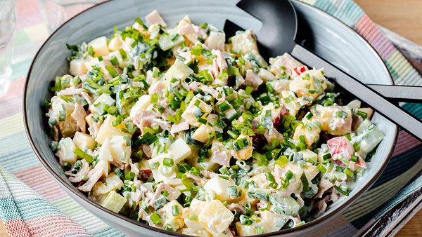 7-Tassen-Salat mit Schnittlauch in einer großen blauen Servierschüssel mit schwarzem Servierbesteck - Foto: House of Food / Bauer Food Experts KG