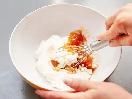 Crème de la Crème Quark und Marmelade werden mit einem Schneebesen in einer Schüssel zu einer cremigen Füllung verrührt.