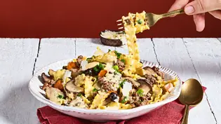 Eine Hand hebt mit einer goldenen Gabel Bandnudeln von einem Teller mit Pilzen, Gemüse, Käse und cremiger Sauce. - Foto: StockFood Studios / Meike Bergmann Eine Hand hebt mit einer goldenen Gabel Bandnudeln von einem Teller mit Pilzen, Gemüse, Käse und cremiger Sauce. - Foto: StockFood Studios / Meike Bergmann
