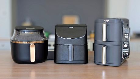 Auf einer Arbeitsfläche aus Holz stehen drei Airfryer nebeneinander: der Philips 3000 Series 6,2L, der Cosori 5,5L XXL und der Ninja Double Stack XL. - Foto: Constanze Brinkschulte / LECKER.de