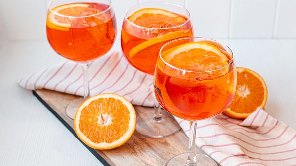 Aperol Spritz in drei Weingläsern mit Orangenscheiben und Eiswürfeln. - Foto: ShowHeroes für LECKER.de