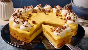 Sahnige Apfel-Eierlikör-Torte mit Rührteig, Apfelschicht und gelber Eierlikörcreme, dekoriert mit Sahnetuffs und Schokoröllchen, auf einer dunklen Kuchenplatte serviert. - Foto: LECKER @ Bauer Media Group Sahnige Apfel-Eierlikör-Torte mit Rührteig, Apfelschicht und gelber Eierlikörcreme, dekoriert mit Sahnetuffs und Schokoröllchen, auf einer dunklen Kuchenplatte serviert. - Foto: LECKER @ Bauer Media Group