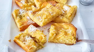Apfelmuskuchen vom Blech ist in Stücke geschnitten und leicht mit Puderzucker bestäubt. - Foto: LECKER @ Bauer Media Group