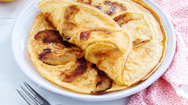 Ein weißer Teller mit zwei goldgelb gebackenen Apfelpfannkuchen einer davon halb umgeklappt - Foto: LECKER @ Bauer Media Group