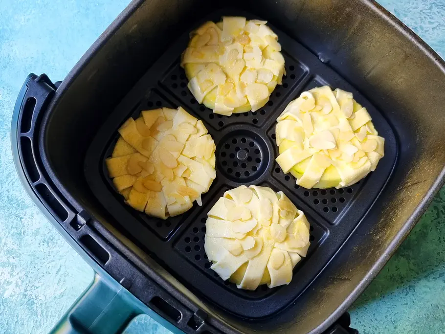 Apfelringe liegen im Garkorb des Airfryers 4 Apfelringe liegen noch ungebacken im Garkorb des Airfryers.
