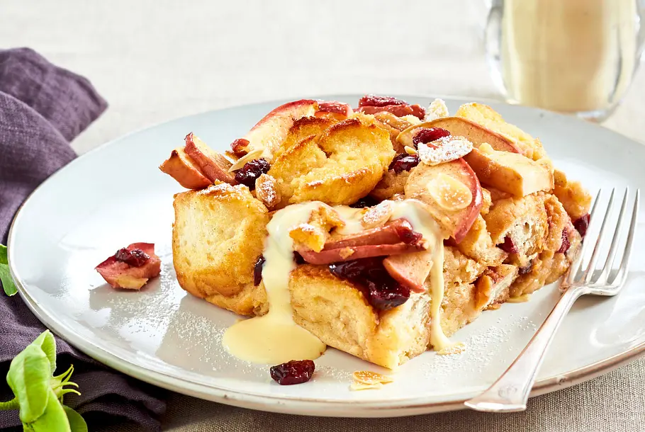 Arme Ritter aus dem Ofen Rezept Arme Ritter mit Äpfeln Cranberrys und Vanillesoße auf weißem Teller.