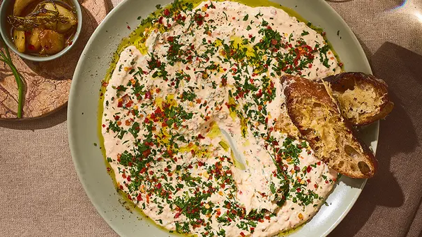 Cremiger Knoblauch-Dip mit Olivenöl, frischen Kräutern und Parmigiano Reggiano, serviert auf einem runden Teller mit knusprigem Brot. - Foto: ITA Assolatte