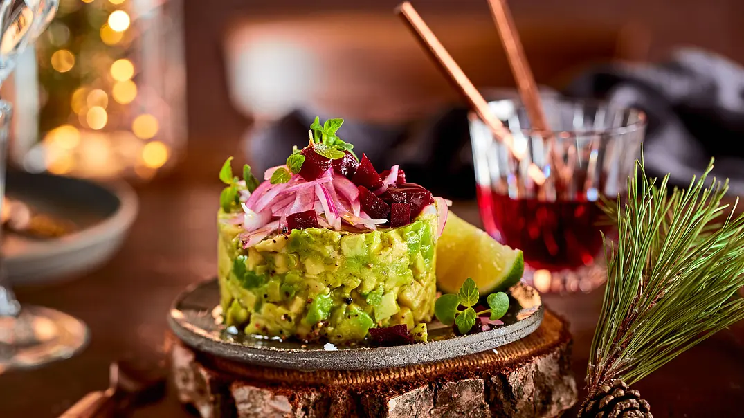 Avocado Tatar mit roten Zwiebeln, Rote-Bete-Würfeln und Limettenstück auf Holzbrett, im festlich dekorierten Ambiente. - Foto: LECKER @ Bauer Media Group Avocado Tatar mit roten Zwiebeln, Rote-Bete-Würfeln und Limettenstück auf Holzbrett, im festlich dekorierten Ambiente. - Foto: LECKER @ Bauer Media Group