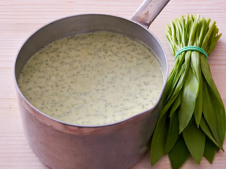 Bärlauch-Hollandaise Rezept Ein Topf mit cremig-grüner Soße und einem Bund Bärlauch daneben.