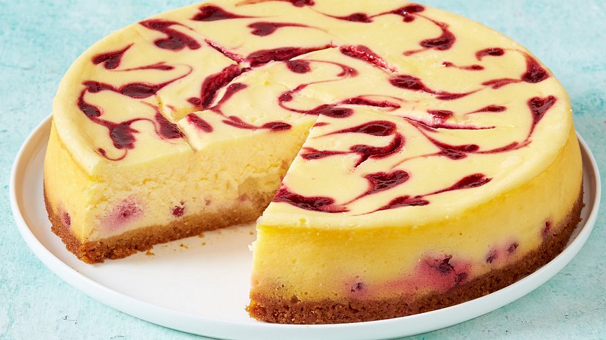 Der Beeren-Käsekuchen mit Zwieback-Boden ist angeschnitten auf einem weißen Teller. - Foto: House of Food / Bauer Food Experts KG