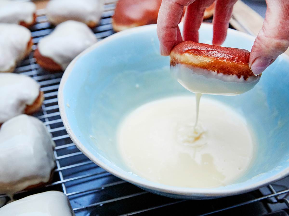 Selbst gemachte Berliner in Zuckerguss tauchen