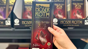 Im Supermarkt hält eine Hand eine Tafel Moser Roth Edelbitter-Schokolade mit 70% Kakao von Aldi  - Foto: LECKER @ Bauer Media Group / Nicole Molitor