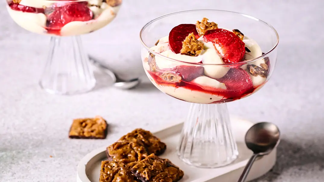 Bienenstich-Dessert mit cremiger Schicht, frischen Pflaumenstücken und knusprigen Mandelkeksen in eleganten Glasschalen, serviert auf hellem Untersetzer mit Löffel und zusätzlichem Gebäck. - Foto: LECKER @ Bauer Media Group Bienenstich-Dessert mit cremiger Schicht, frischen Pflaumenstücken und knusprigen Mandelkeksen in eleganten Glasschalen, serviert auf hellem Untersetzer mit Löffel und zusätzlichem Gebäck. - Foto: LECKER @ Bauer Media Group