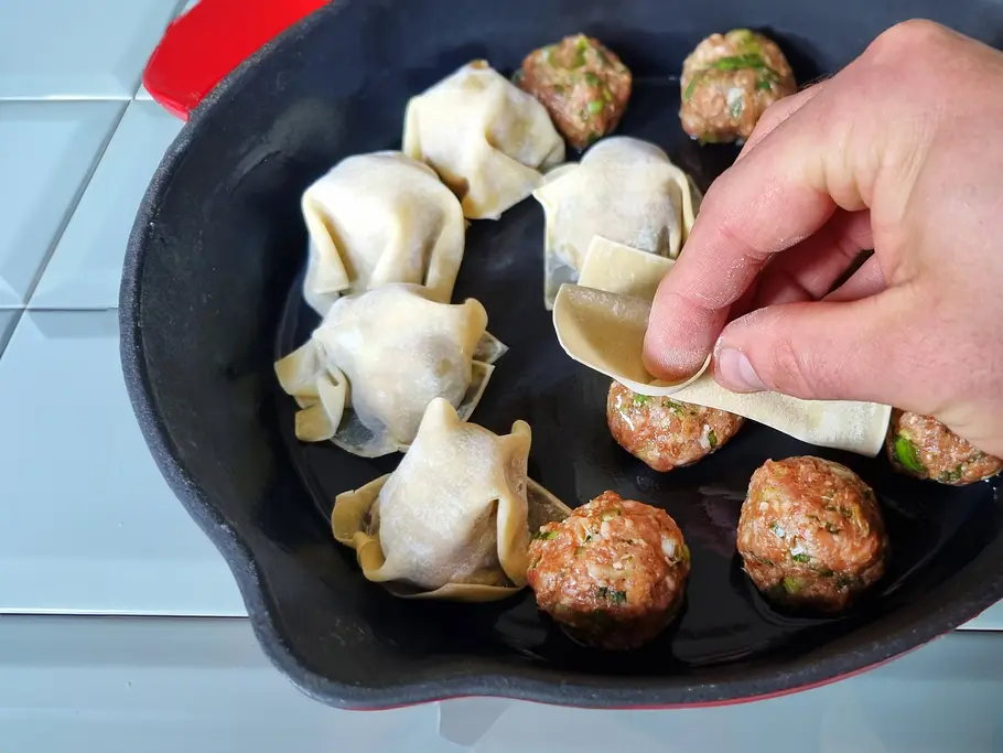 Dumplings werden in der Pfanne mit Wan-Tan-Teig bedeckt.