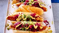 Bratwurst im Brötchen mit saftigem Kraut-Topping auf einem Blechteller serviert. - Foto: LECKER @ Bauer Media Group