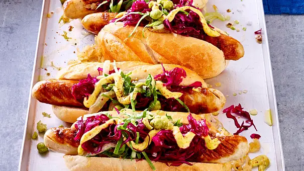 Bratwurst im Brötchen mit saftigem Kraut-Topping auf einem Blechteller serviert. - Foto: LECKER @ Bauer Media Group Bratwurst im Brötchen mit saftigem Kraut-Topping auf einem Blechteller serviert. - Foto: LECKER @ Bauer Media Group