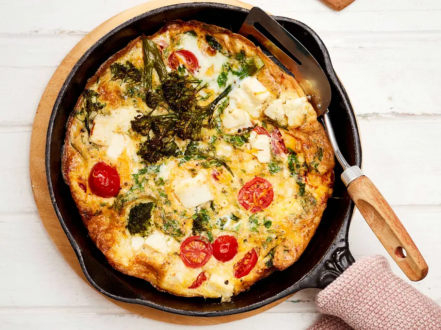 Brokkoli-Frittata rot-weiß Rezept Brokkoli-Frittata mit Tomaten und Käse in einer Pfanne präsentiert.