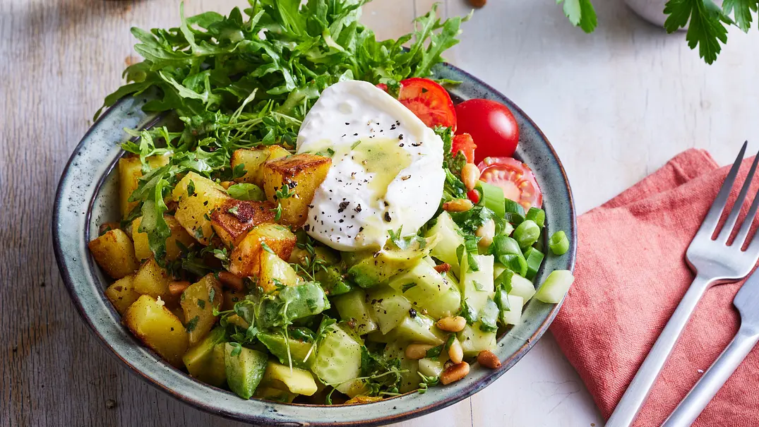 Geröstete Kartoffelwürfel, Gurkenwürfel, Rucola und Tomatenhälften in einem tiefen Teller angerichtet mit einer aufgeschnittenen Burratakugel in der Mitte. - Foto: LECKER @ Bauer Media Group Geröstete Kartoffelwürfel, Gurkenwürfel, Rucola und Tomatenhälften in einem tiefen Teller angerichtet mit einer aufgeschnittenen Burratakugel in der Mitte. - Foto: LECKER @ Bauer Media Group