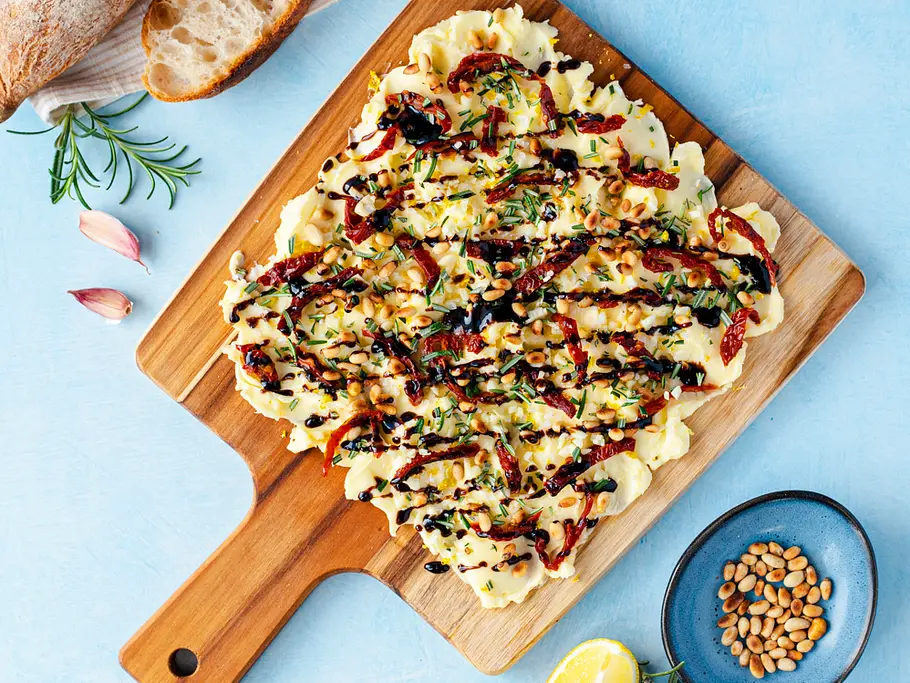 Mediterranes Butter Board Butter Board mit Rosmarin, getrockneten Tomaten, Knoblauch und Rosmarin.