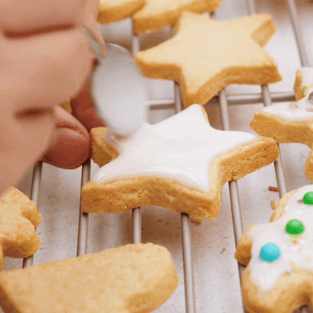 Butterplätzchen werden mit Zuckerguss eingestrichen und Streuseln verziert.