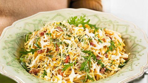Cremiger Spaghetti-Salat nach Carbonara-Art mit Rucola, Speck, geriebenem Käse auf einem dekorativen Keramikteller - Foto: House of Food / Bauer Food Experts KG