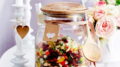 Chili sin carne Salat in einem großen Glas mit Holzdeckel und Holzlöffel auf einem Tisch. - Foto: LECKER @ Bauer Media Group