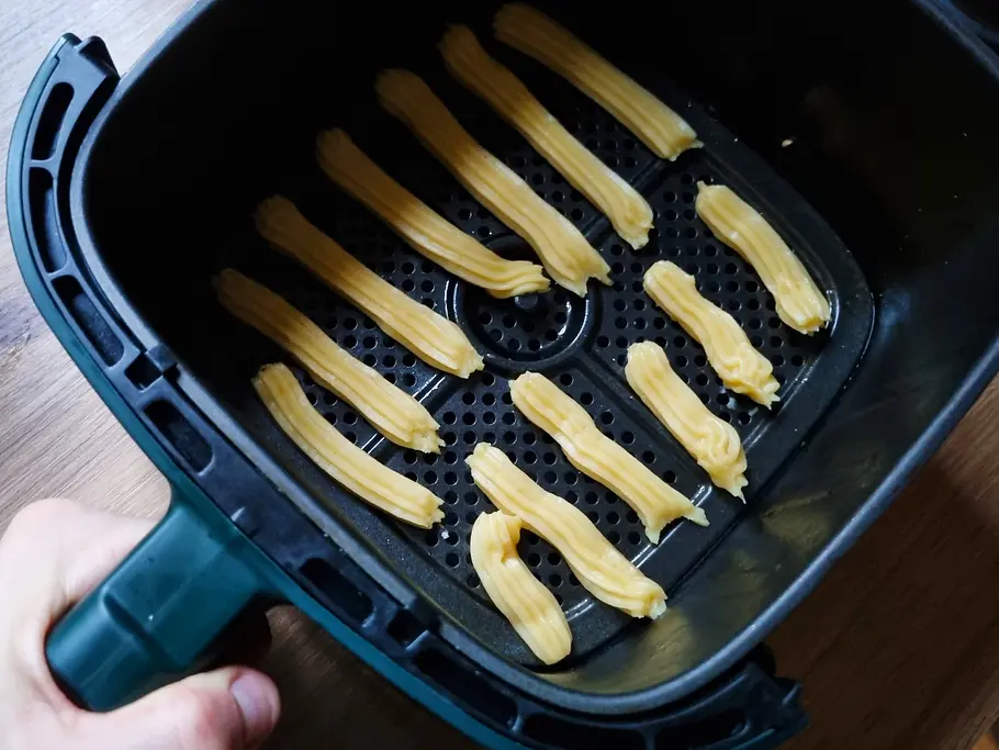 Die ungebackenen Churros liegen im Garkorb des Airfryers.