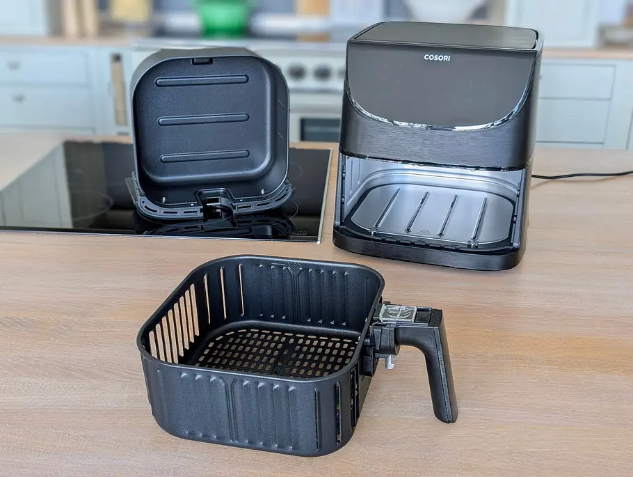 Die Einzelteile der Cosori 5,5L XXL Heißluftfritteuse Die Cosori 5,5L XXL Heißluftfritteuse steht auf einer Arbeitsfläche, daneben die zwei Teile der Schublade