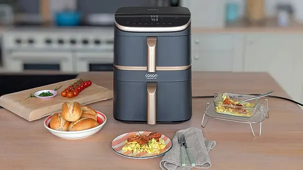 Der Cosori Turbo Tower Pro Smart steht auf einer Arbeitsfläche. Davor liegen Brötchen in einer Schale, Rührei mit Bacon auf einem Teller, Besteck und eine Glasform mit fertigem Rührei auf dem Gitterrost des Airfryers. Im Hintergrund liegen Schnittlauch und Tomaten auf einem Holzbrett. - Foto: LECKER @ Bauer Media Group / Constanze Brinkschulte Der Cosori Turbo Tower Pro Smart steht auf einer Arbeitsfläche. Davor liegen Brötchen in einer Schale, Rührei mit Bacon auf einem Teller, Besteck und eine Glasform mit fertigem Rührei auf dem Gitterrost des Airfryers. Im Hintergrund liegen Schnittlauch und Tomaten auf einem Holzbrett. - Foto: LECKER @ Bauer Media Group / Constanze Brinkschulte
