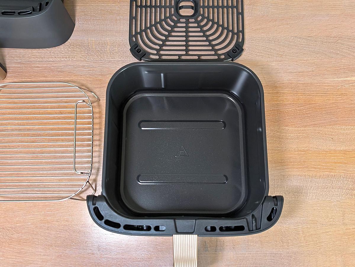 Schublade des Cosori Turbo Tower Pro Smart Blick von oben auf eine Arbeitsfläche, auf der eine leere Schublade des Cosori Turbo Tower Pro Smart liegt. Ringsherum liegen die Röstplatte, der Bratrost und die zweite Schublade.