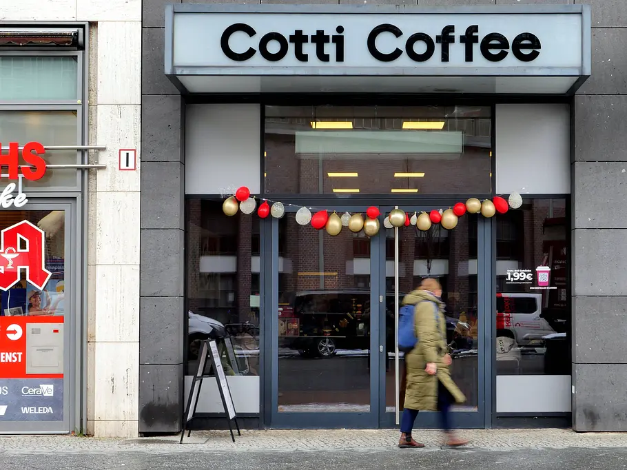 Cotti Coffee - Shop in Berlin Cotti Coffee-Shop in Berlin zur Eröffnung mit Luftballons dekoriert. Eine Person schaut neugierig durch die Fensterfront.