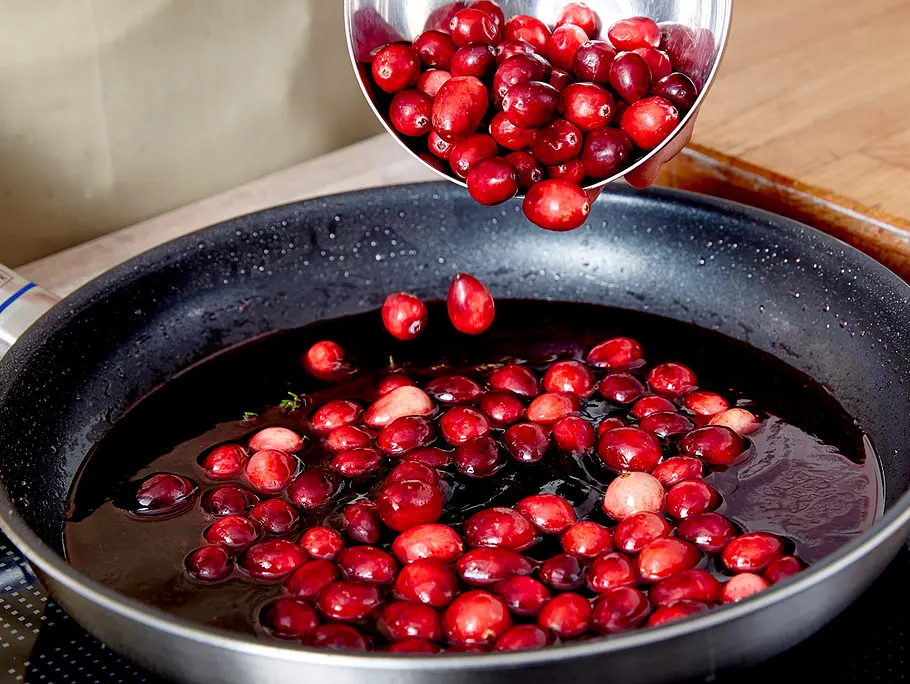 Cranberrys zu Wasser-Zucker-Orangesaft-Mix in die Pfanne geben