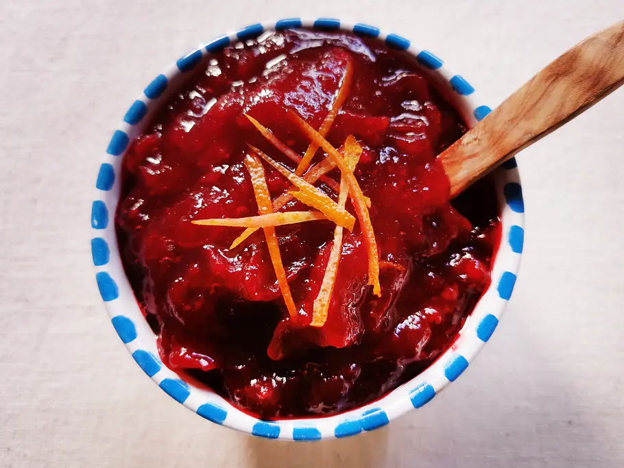 Cranberry-Sauce mit Orangenzesten in einer blau-weißen Schale mit Holzlöffel