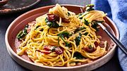 Cremige Miso-Carbonara mit Speck und Babyspinat auf einem terakottafarbenen Teller mit einer Gabel - Foto: House of Food / Bauer Food Experts KG