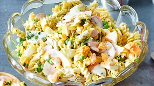 Nudelsalat mit Ei, Mayonnaise, Erbsen und Fleischwurst in einer Glasschale mit welligem Rand. - Foto: LECKER @ Bauer Media Group
