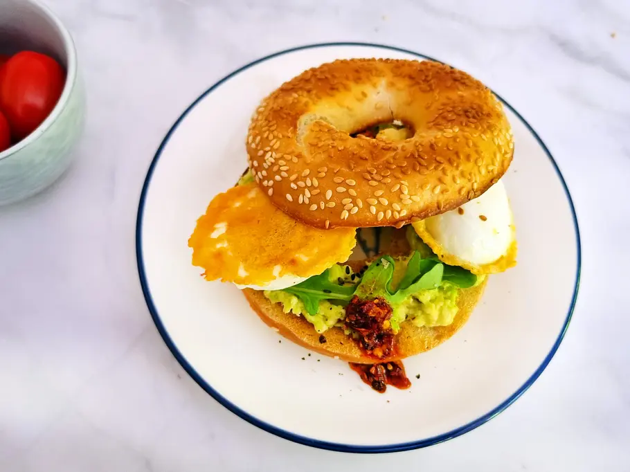 Knusprige Käse-Eier auf Bagel mit Avocado, Rukola und Chili-Öl.