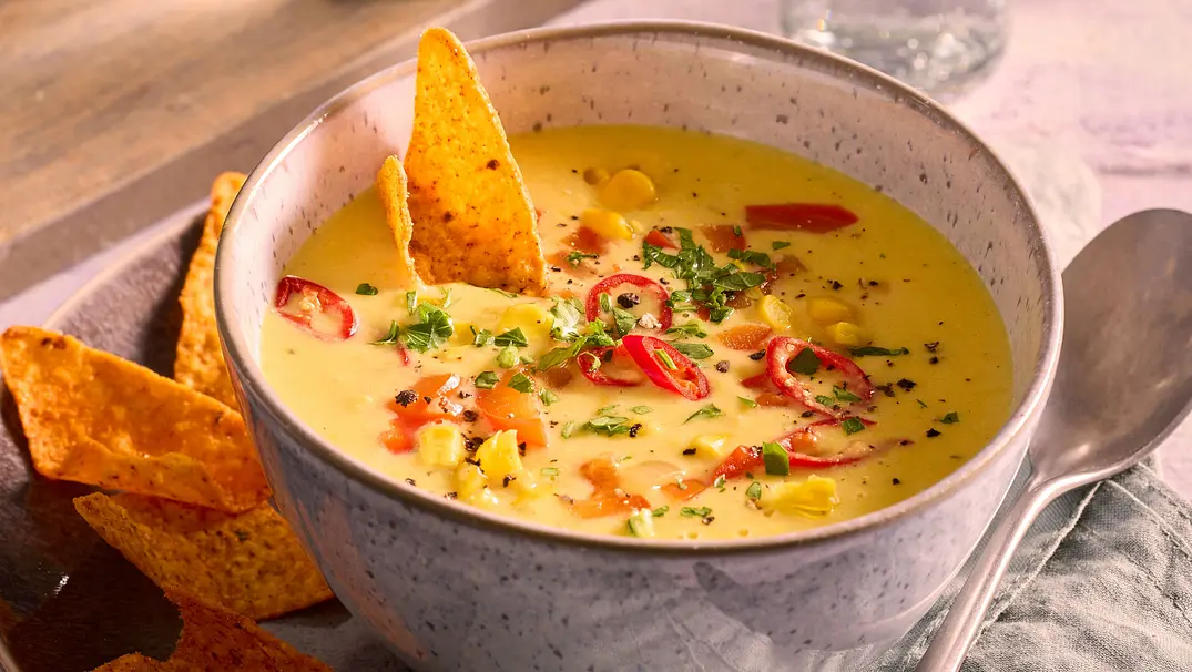 Cremige Curry-Mais-Suppe mit Mais, Paprika, Chili und frischen Kräutern, serviert mit knusprigen Tortilla-Chips. - Foto: LECKER @ Bauer Media Group