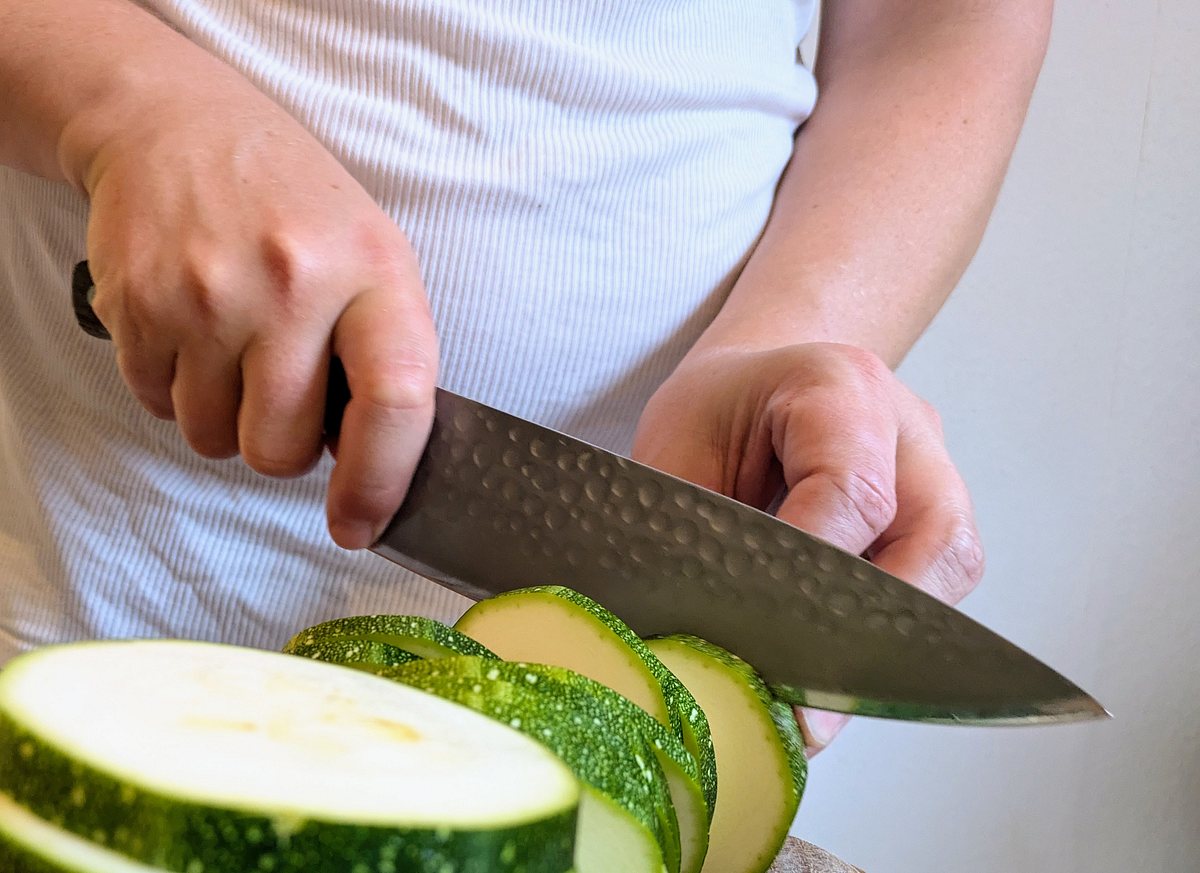 F. Dick DarkNitro Kochmesser Zucchini Mit dem DarkNitro Kochmesser von F. Dick schneidet jemand eine große Zucchini in Scheiben.