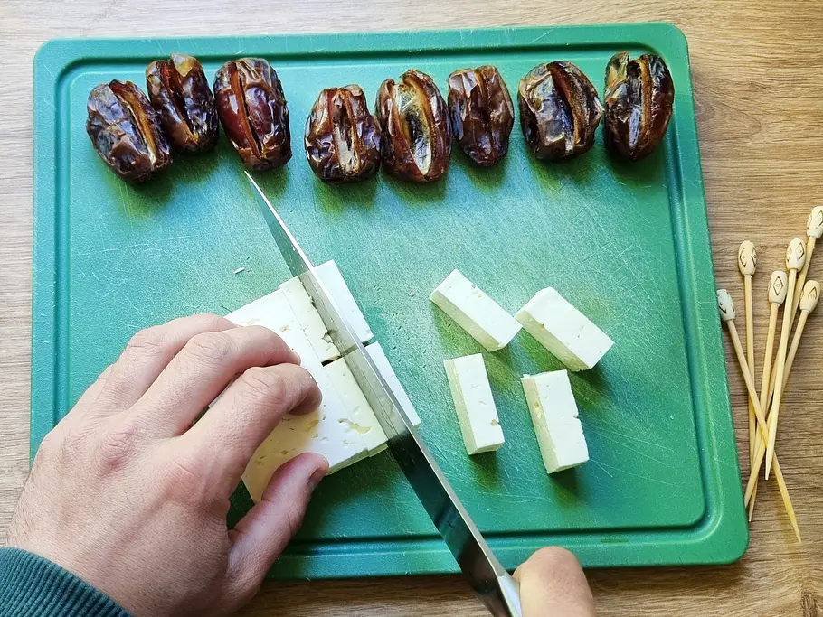 Dattel-Feta-Spieße zubereiten Feta wird in Stücke geschnitten und auch die halbierten Datteln sind gut zu erkennen.