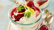 Ein kleine Glasschale gefüllt mit Zitronencreme mit einem Topping aus angedickten Kirschen, Zitronenzesten und Zitronenmelisse-Blättchen. - Foto: House of Food / Bauer Food Experts KG