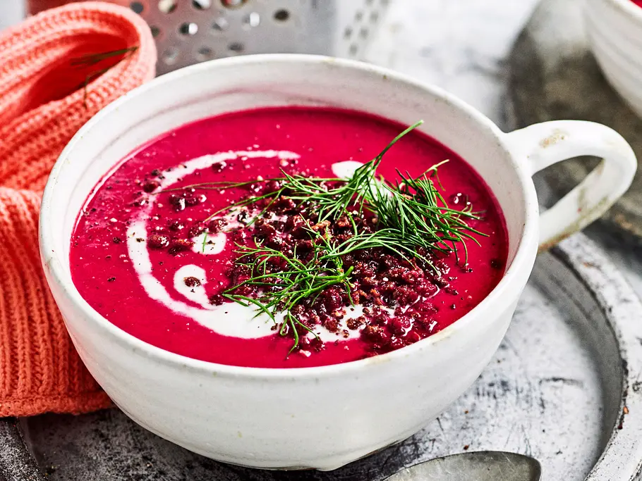 Rote Bete Suppe mit Dill und Joghurt-Swirl garniert in einer weißen Suppenschale