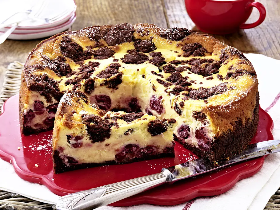 Eierlikör-Zupfkuchen aus der Springform, auf einer roten Kuchenplatte, mit Puderzucker bestäubt