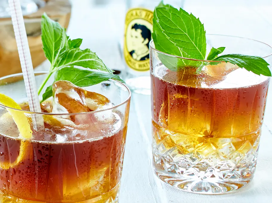 Zwei Gläser gefüllt mit einer Schicht Tonic Water, darauf Espresso und Eiswürfel. Garniert mit Minzeblättern und Zitronenschale.