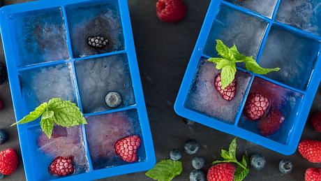 Zwei Eiswürfelformen aus Silikon mit frischen tiefgefrorenen Beeren dekoriert - Foto: i-Stock/arinahabich
