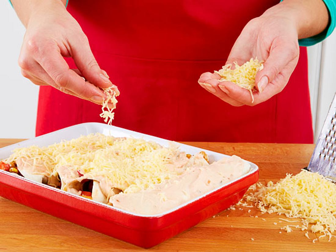 Enchiladas mit geriebenem Käse bestreuen