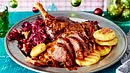 Knusprig gebratene Entenkeule mit Rotkohl und Kartoffelklößen auf einem Teller angerichtet, festlich dekoriert mit Weihnachtskugeln im Hintergrund. - Foto: LECKER @ Bauer Media Group Knusprig gebratene Entenkeule mit Rotkohl und Kartoffelklößen auf einem Teller angerichtet, festlich dekoriert mit Weihnachtskugeln im Hintergrund. - Foto: LECKER @ Bauer Media Group
